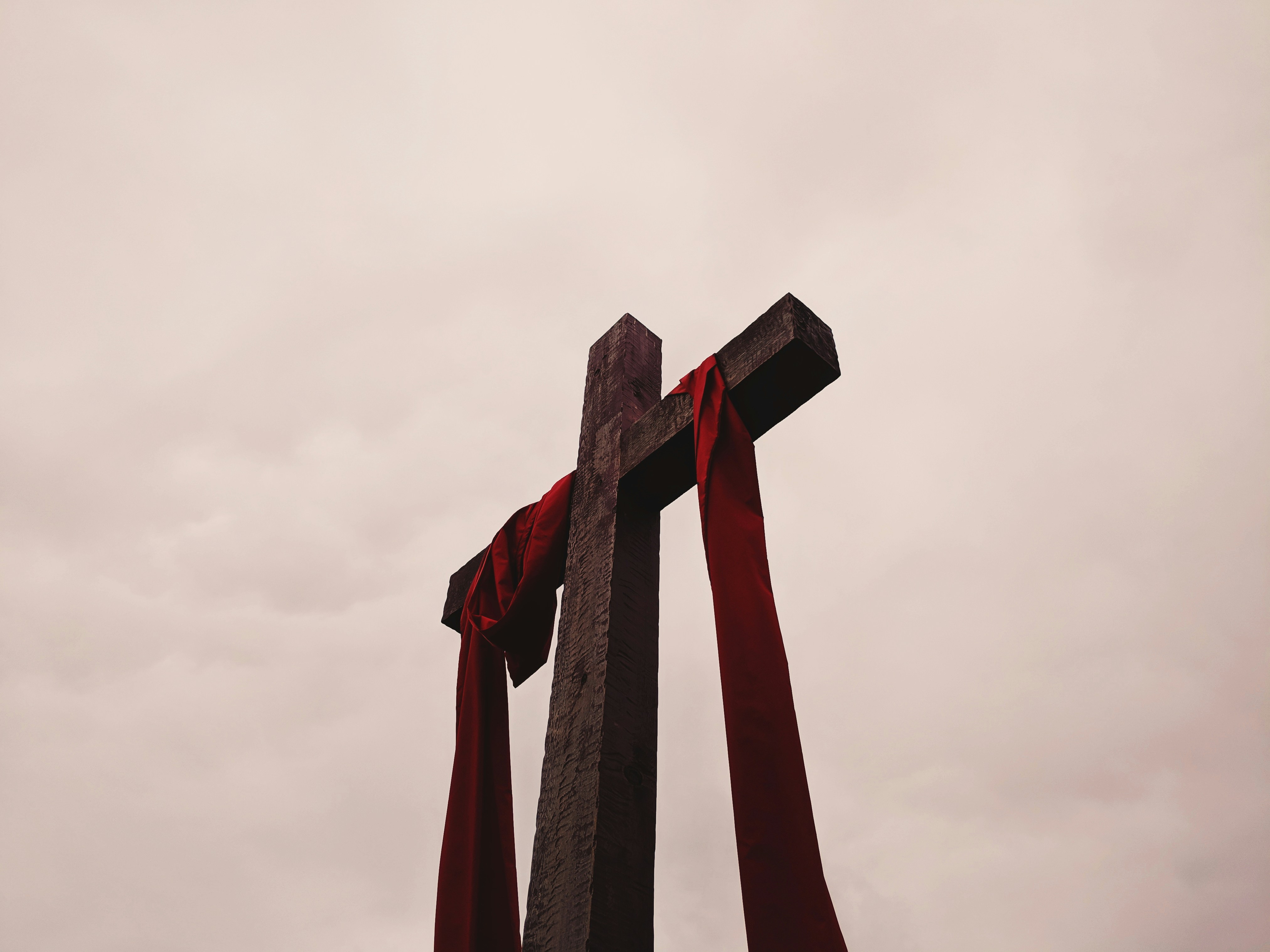 a wooden cross with a scarlet cloth wrapped around its arms